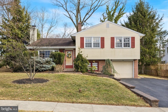 tri-level home with brick siding, driveway, a chimney, and a front lawn