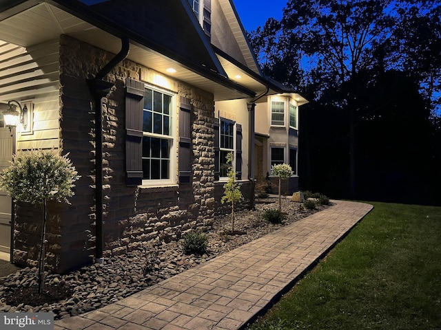 view of side of property featuring a yard and stone siding