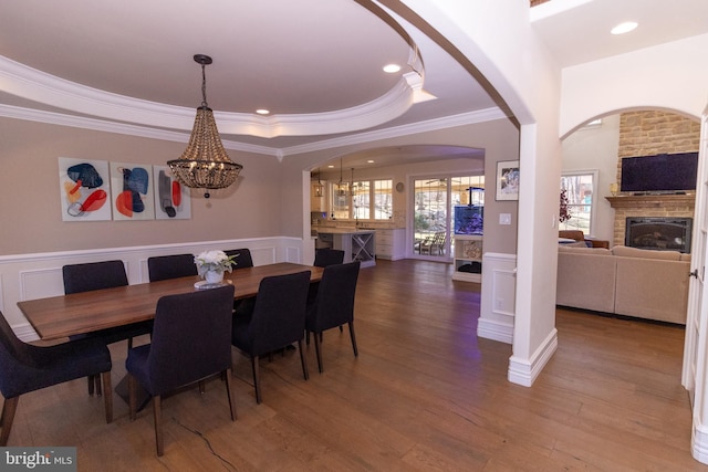 dining room featuring a wainscoted wall, a tray ceiling, wood finished floors, a decorative wall, and a chandelier