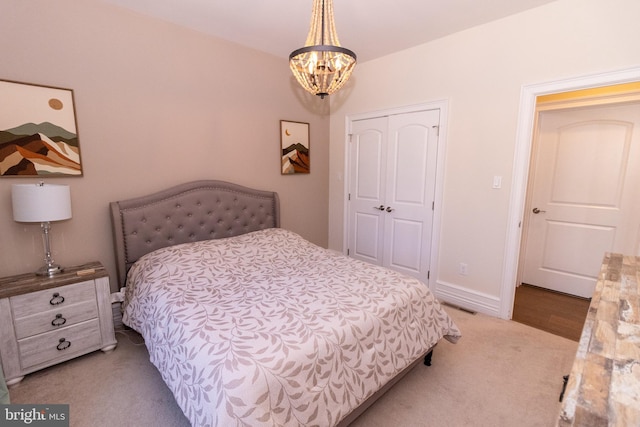 bedroom featuring visible vents, baseboards, light colored carpet, a closet, and a notable chandelier
