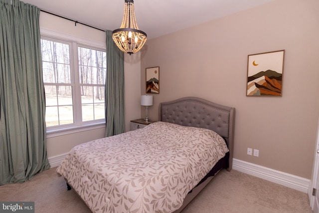 bedroom with an inviting chandelier, light colored carpet, and baseboards