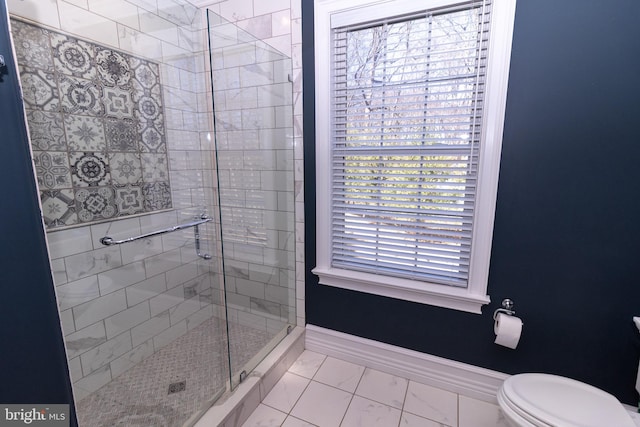 bathroom with baseboards, toilet, marble finish floor, and a stall shower