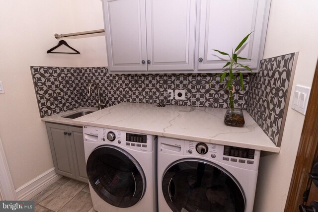 laundry area with cabinet space, washing machine and dryer, baseboards, and a sink