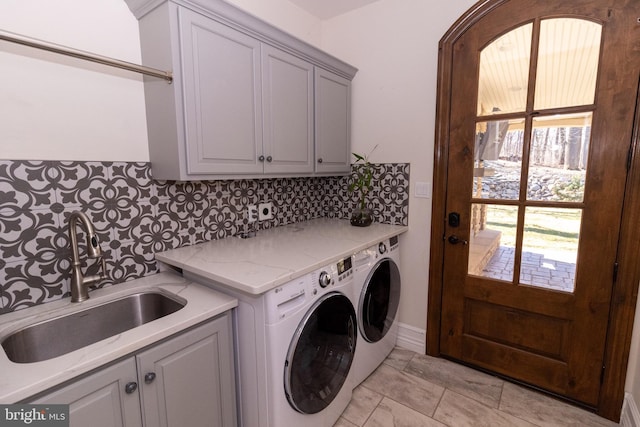 washroom with washing machine and clothes dryer, cabinet space, and a sink