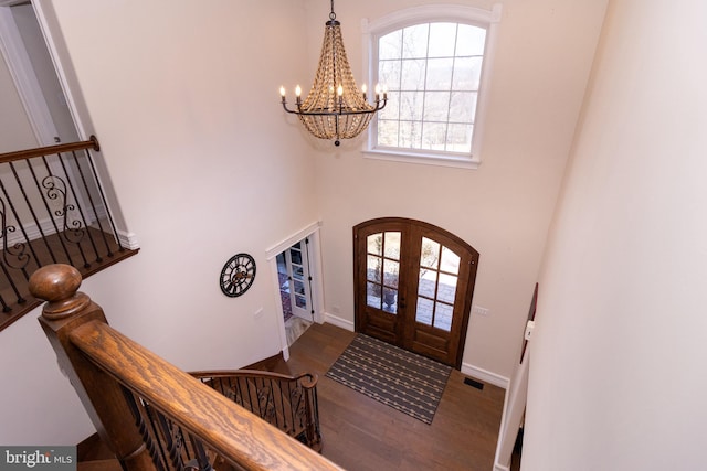 entrance foyer with stairway, wood finished floors, visible vents, french doors, and a chandelier
