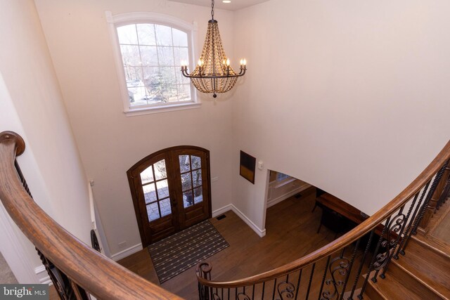 foyer entrance with wood finished floors, visible vents, arched walkways, french doors, and a chandelier