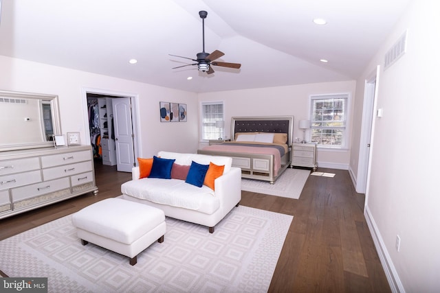 bedroom featuring a spacious closet, visible vents, wood finished floors, and vaulted ceiling