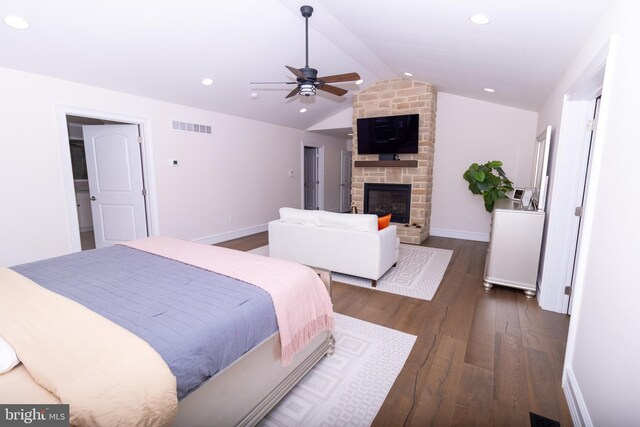 bedroom with wood finished floors, visible vents, baseboards, lofted ceiling, and a fireplace