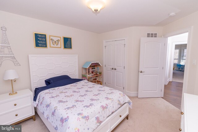bedroom featuring visible vents, a closet, and light carpet