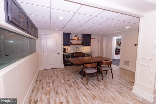 dining space with wet bar, visible vents, beverage cooler, and light wood-style floors