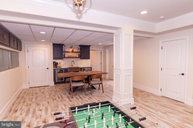 rec room with beverage cooler, light wood finished floors, wet bar, and baseboards