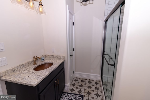 full bath featuring vanity, tile patterned floors, baseboards, and a stall shower