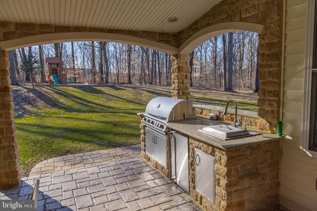 view of patio featuring grilling area, exterior kitchen, and a playground