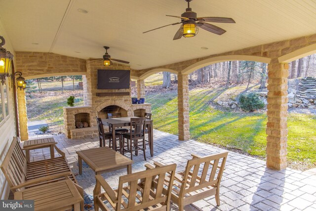 view of patio / terrace with an outdoor living space with a fireplace and ceiling fan