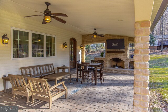 view of patio featuring outdoor dining space, a ceiling fan, and an outdoor living space with a fireplace