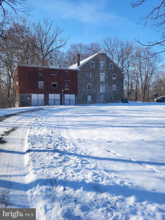 snow covered house featuring a chimney