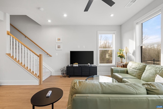 living area featuring plenty of natural light, visible vents, stairway, and wood finished floors