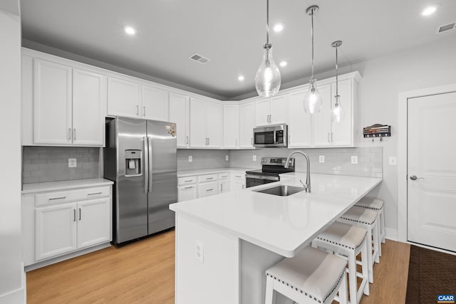 kitchen featuring visible vents, white cabinets, appliances with stainless steel finishes, a breakfast bar, and a peninsula