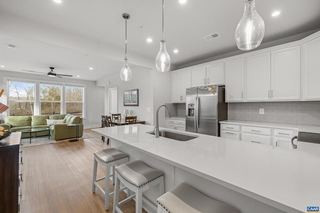 kitchen with stainless steel fridge, tasteful backsplash, visible vents, light countertops, and a sink