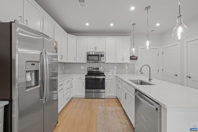 kitchen with stainless steel appliances, a peninsula, a sink, visible vents, and light countertops