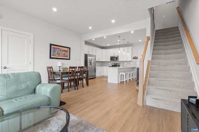 living area featuring light wood-style floors, stairs, visible vents, and recessed lighting