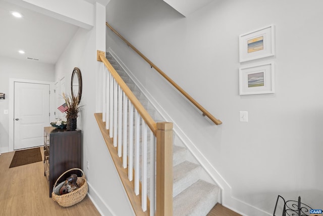 stairway featuring baseboards, wood finished floors, visible vents, and recessed lighting