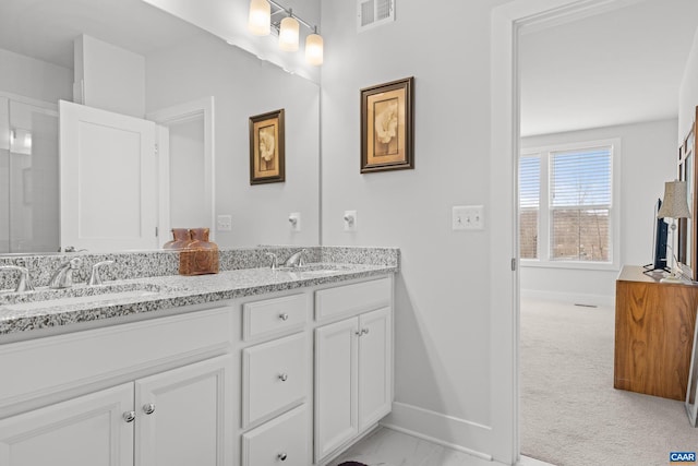 bathroom with baseboards, visible vents, and a sink