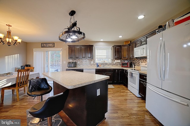 kitchen featuring white appliances, light countertops, a sink, and light wood finished floors