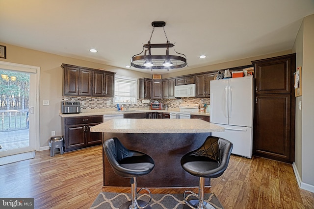 kitchen with light wood-style flooring, dark brown cabinetry, white appliances, light countertops, and decorative backsplash