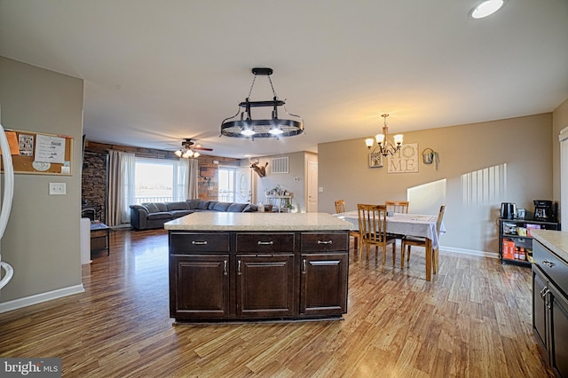 kitchen with open floor plan, hanging light fixtures, dark brown cabinetry, and light wood-style floors