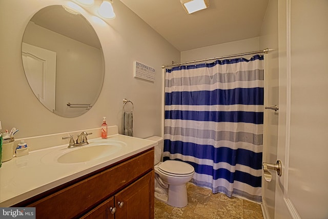 bathroom with curtained shower, stone finish floor, vanity, and toilet