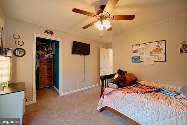 bedroom with light colored carpet, a ceiling fan, baseboards, a closet, and a walk in closet