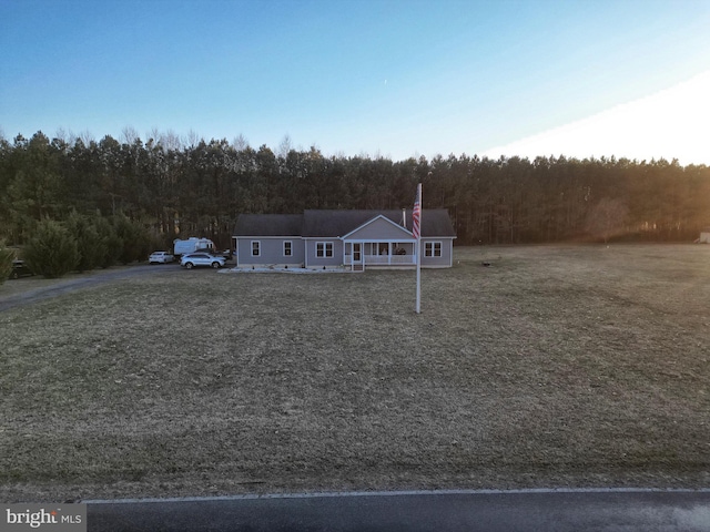 view of front of property featuring a front lawn and a forest view