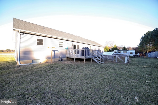 back of house with a deck, a lawn, and roof with shingles