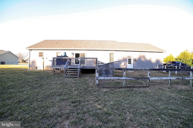 back of house featuring fence, a lawn, and a wooden deck