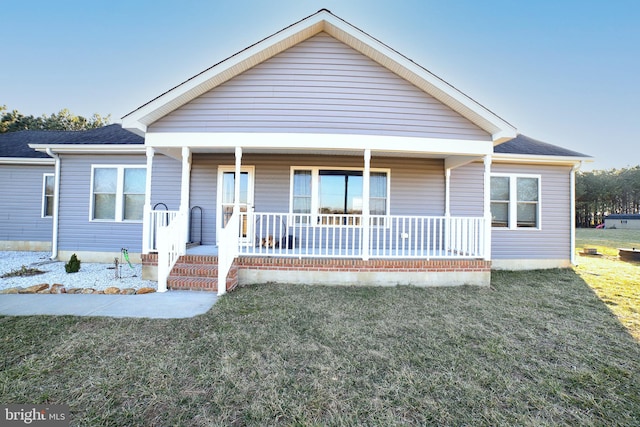 view of front of property featuring a porch, roof with shingles, and a front lawn