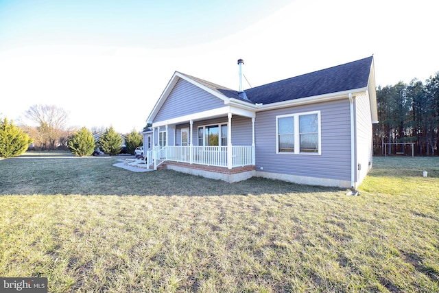 back of property with covered porch, a lawn, and roof with shingles