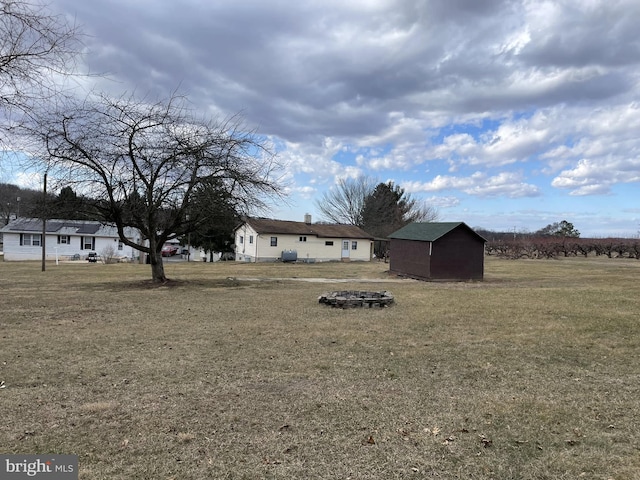 view of yard with an outdoor fire pit, a shed, and an outdoor structure