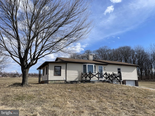 view of front of home with a garage, a chimney, and a wooden deck