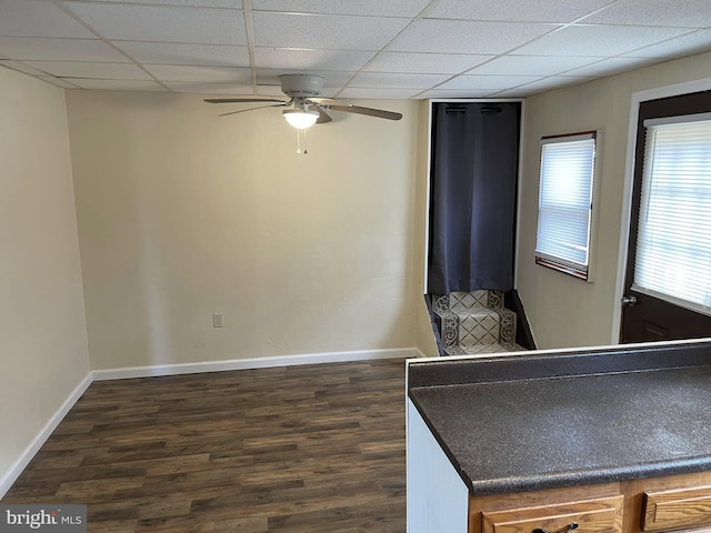 bedroom featuring a ceiling fan, baseboards, a drop ceiling, and dark wood-style flooring