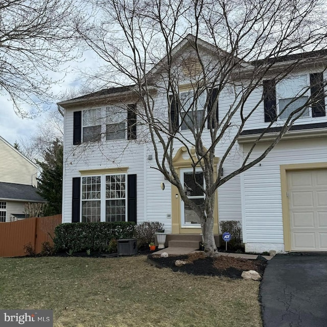 traditional-style home featuring a garage, fence, a front yard, and entry steps