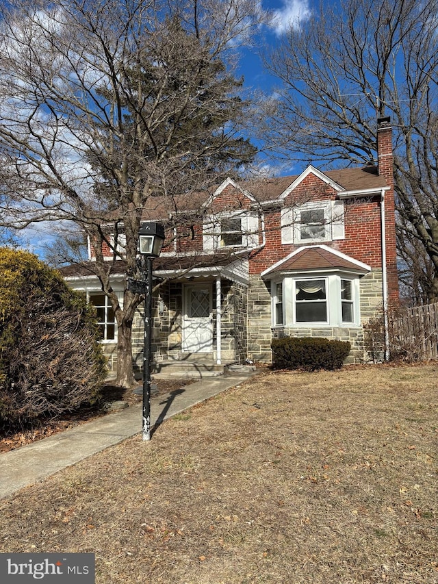 view of front of home featuring stone siding, brick siding, and a chimney