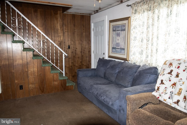 living room featuring stairway, wooden walls, and carpet flooring