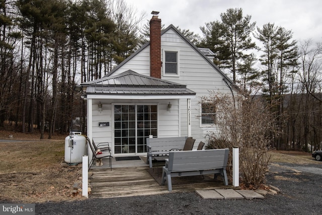 back of house with a chimney and metal roof