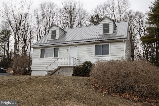 cape cod home featuring metal roof