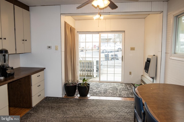 kitchen with heating unit, wood finished floors, white cabinetry, butcher block counters, and ceiling fan