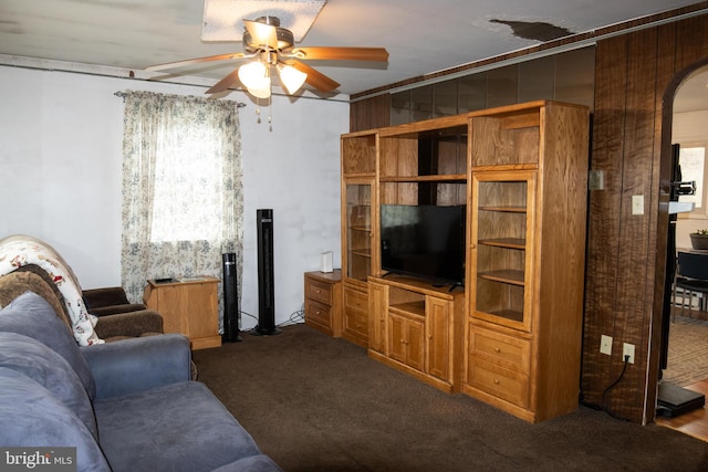 carpeted living area with arched walkways and a ceiling fan