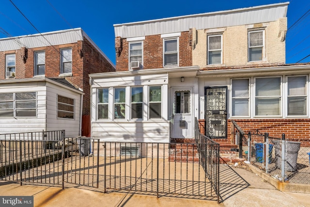 view of property featuring entry steps, brick siding, a fenced front yard, and cooling unit