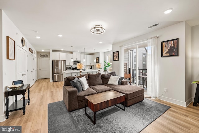 living room with baseboards, light wood-style flooring, visible vents, and recessed lighting