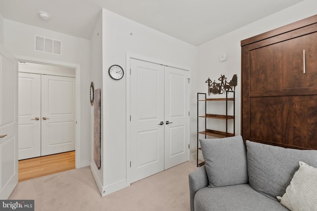 living area with baseboards, visible vents, and light colored carpet